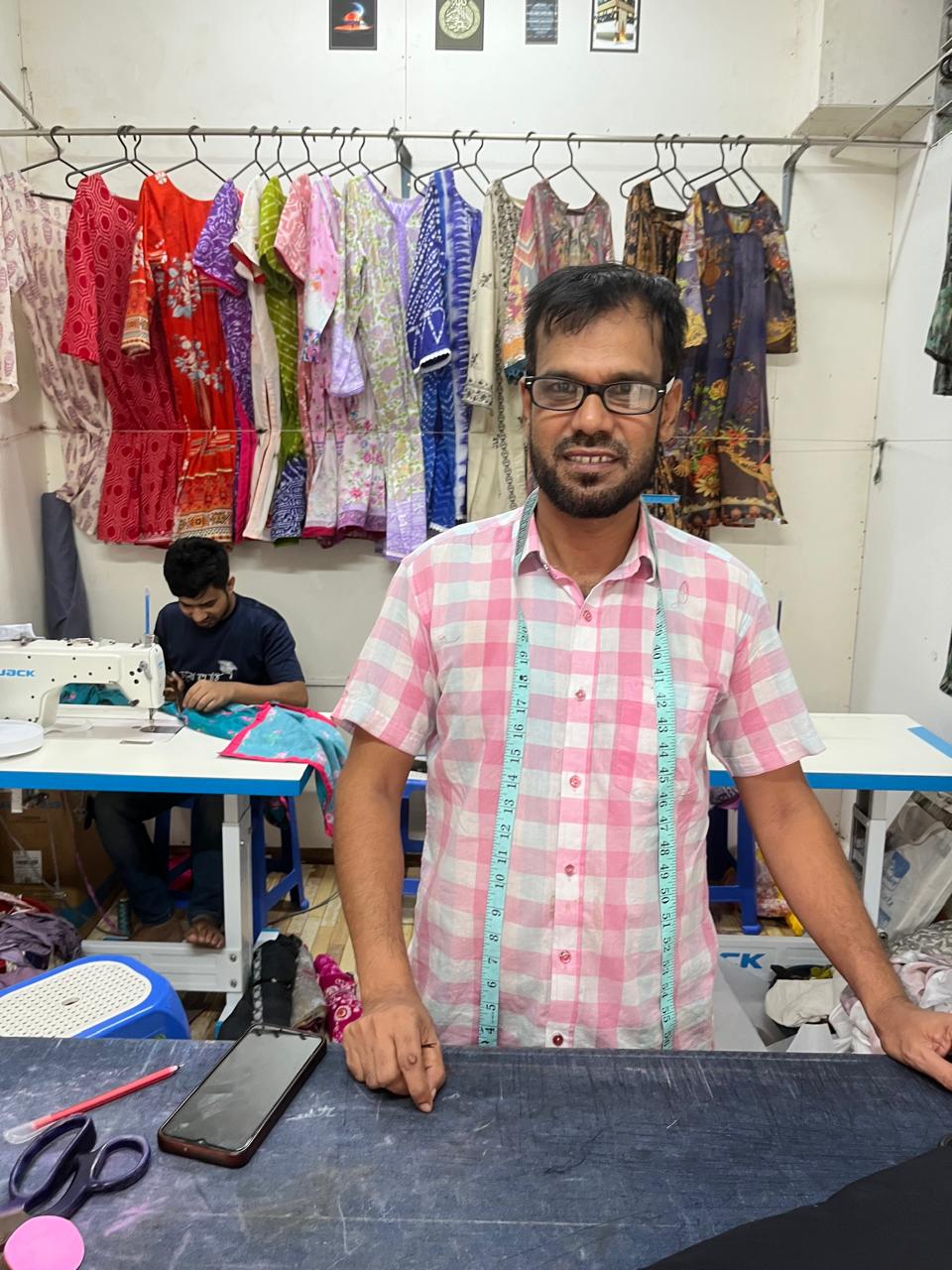Cutting Master Abul Kashem at the cutting table measuring and preparing fabric patterns at Simon Morsh Boutique House
